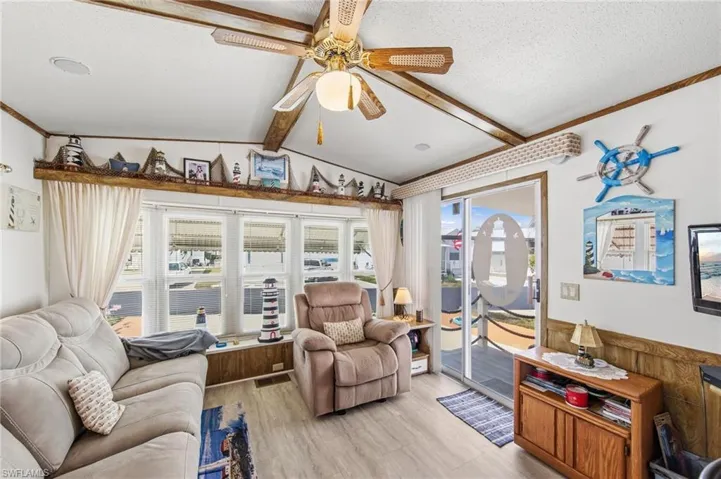 Living room featuring ceiling fan, beamed ceiling, and light wood finished floors
