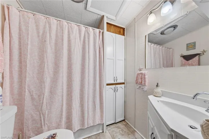 Bathroom featuring tile walls, vanity, and shower / bath combo with shower curtain