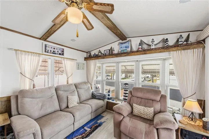 Living area with lofted ceiling with beams and ceiling fan