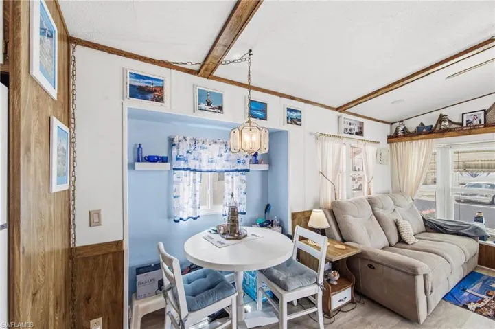 Living room featuring healthy amount of natural light, hanging lights, beamed ceiling, and wood finished floors