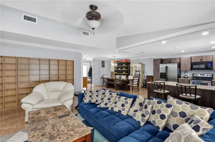 Open-concept living area featuring tile flooring, a ceiling fan, recessed lighting, and a built-in shelving unit