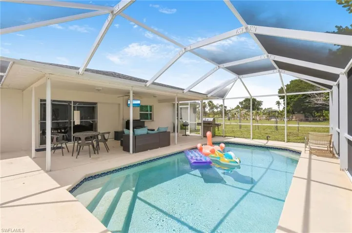 Screened-in outdoor pool featuring a concrete patio surround and integrated steps