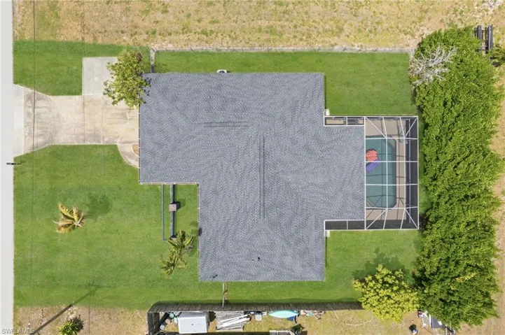 Property featuring a private screened pool enclosure, a dark shingle roof, and a concrete driveway