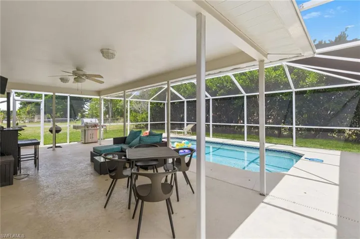 Screened outdoor living area featuring a covered patio, ceiling fan, and in-ground swimming pool