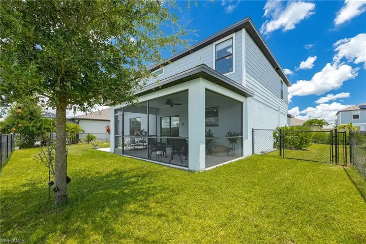 Rear view of property with a patio, ceiling fan, and a yard