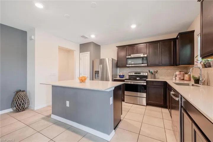 Kitchen with a center island, stainless steel appliances, sink, tasteful backsplash, and light tile floors