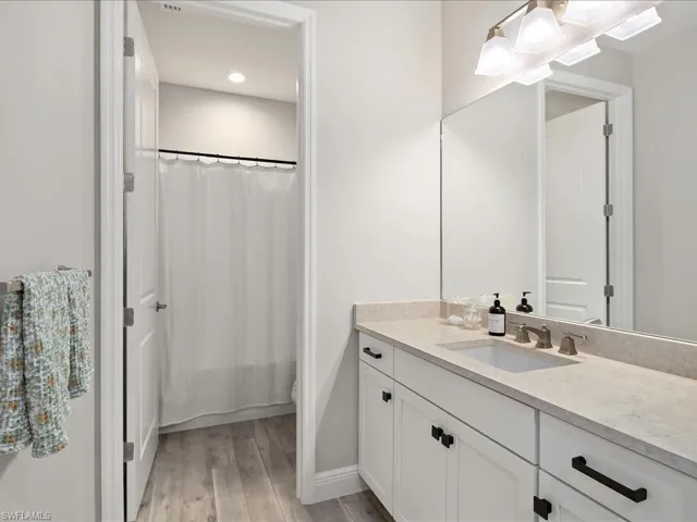 Bathroom featuring a single vanity with stone-finish countertop, undermount sink, and dark-toned hardware