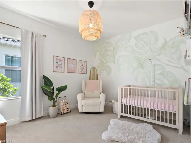 Light-filled room featuring a decorative accent wall, recessed window, light-colored carpeting, and a woven pendant light fixture