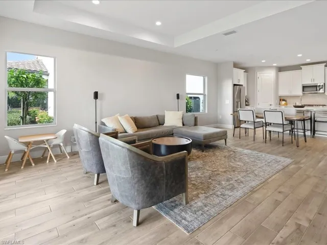 Open-concept living space featuring wood-finish flooring, recessed lighting, and a tray ceiling