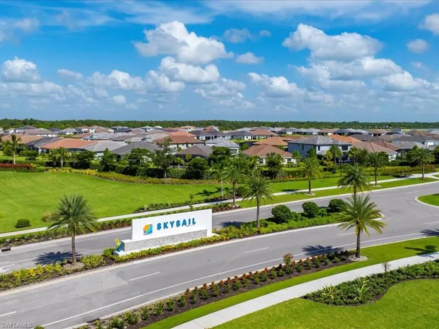 Community entrance featuring a SkySail monument sign, manicured landscaping, paved streets, and a collection of single-family homes with diverse rooflines