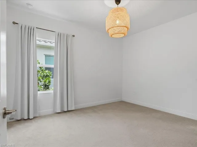Carpeted room featuring a double-hung window with drapery and a woven pendant light fixture