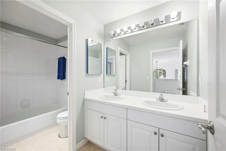 Bathroom with double vanity featuring white cabinetry, dual undermount sinks, and a single expansive mirror
