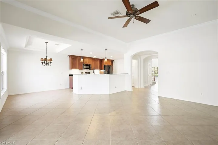 Expansive living area featuring large format tile flooring, crown molding, and an arched entryway