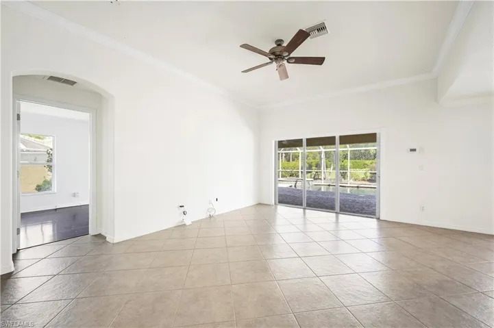 Spacious interior featuring neutral tile flooring, crown molding, and a vaulted ceiling with a ceiling fan