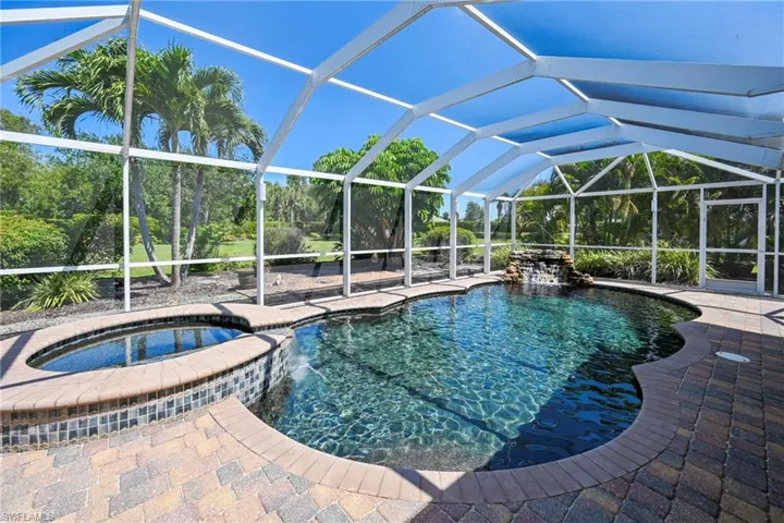 Screened lanai featuring a freeform swimming pool and integrated spa