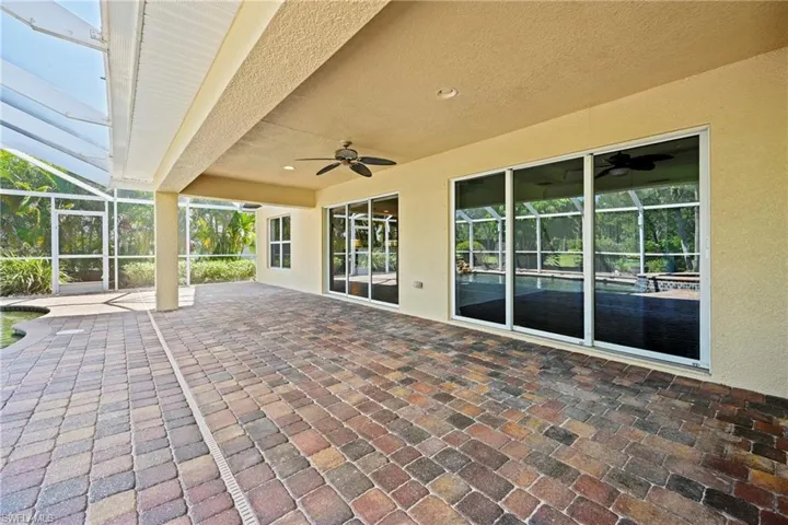 Expansive screened lanai with brick paver flooring and an overhead ceiling fan