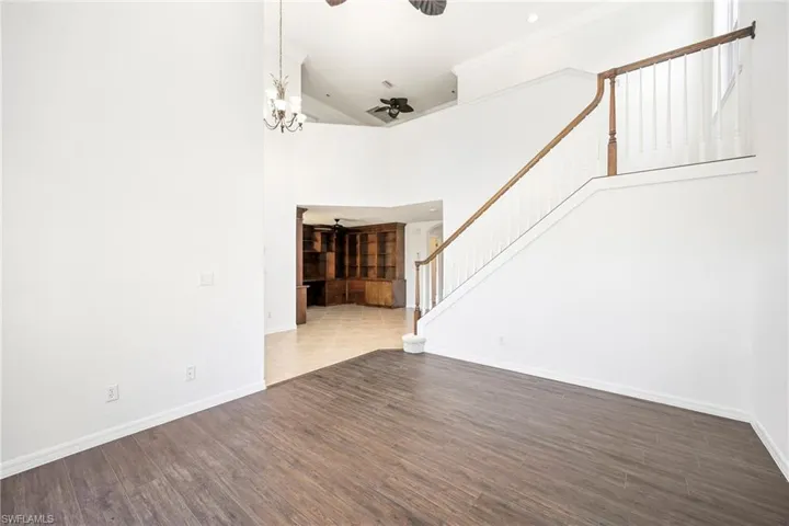 Expansive interior featuring wood-finish flooring, a grand staircase with white balusters and wood handrail, and high ceilings
