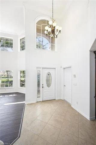 Foyer with high ceilings, an arched transom window, and a decorative chandelier