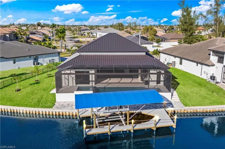 View of the home from the back - an expansive outdoor area with outdoor kitchen, pool and spa, disappearing sliders and a boatlift with canopy, outdoor lighting and trexdeck to last a lifetime!