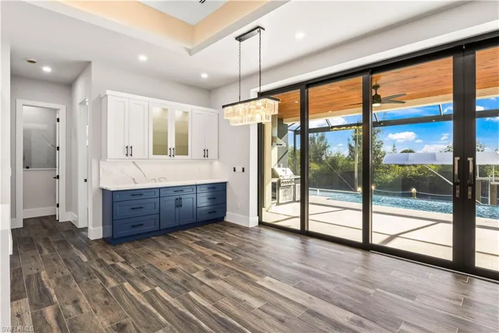 Dining area with built in 42 inch cabinets with display lights, cambria quartz backsplash and easy access to the outside.