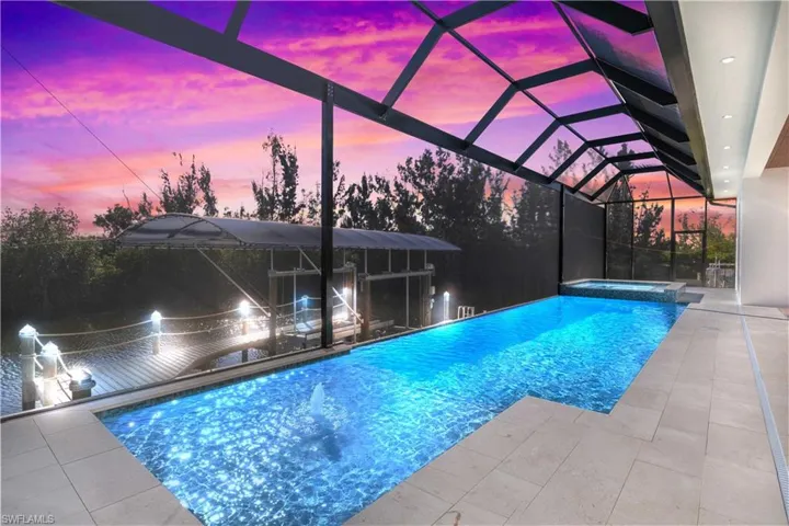Night time view of the outdoor area.  Heated pool with large sunshelf and cascading spa make the perfect relaxation spot to enjoy out beautiful Florida evenings.  12,000 pound boat lift with beautiful lighting as well!