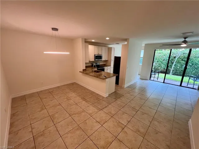 Kitchen with light tile patterned flooring, white cabinets, kitchen peninsula, and stainless steel appliances