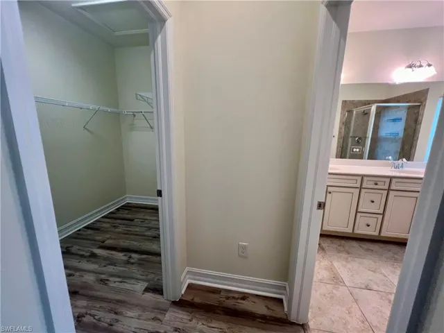 Bathroom with a shower with door, luxury vinyl plank / wood-style floors, and double vanity