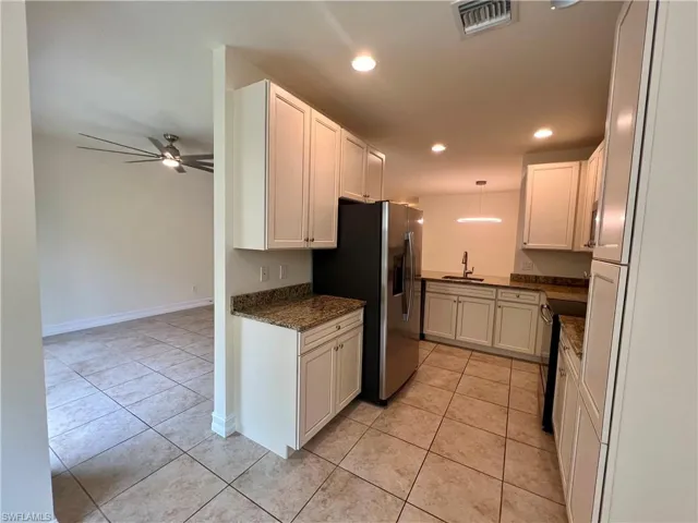 Kitchen featuring white cabinets, light tile patterned floors, sink, and ceiling fan