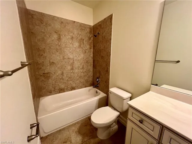 Full bathroom with vanity, toilet, tile patterned floors, and tiled shower / bath