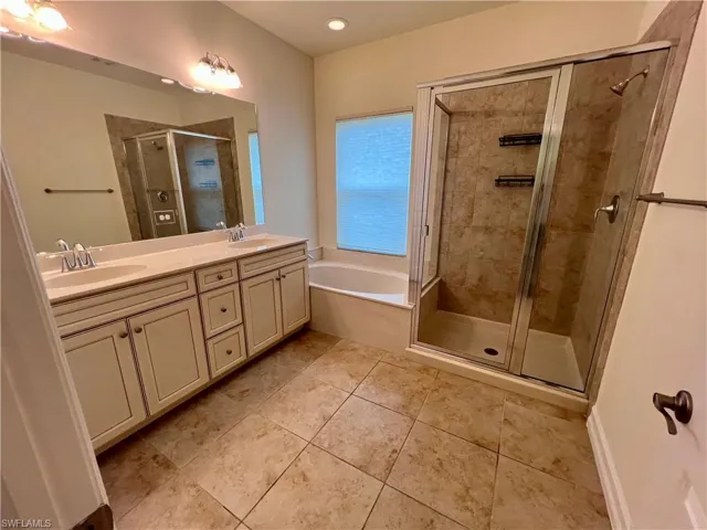 Bathroom featuring separate shower and tub, tile patterned floors, and dual bowl vanity