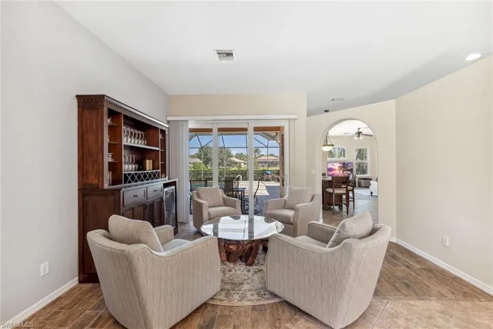 Living room featuring arched walkways, visible vents, baseboards, and wood finished floors
