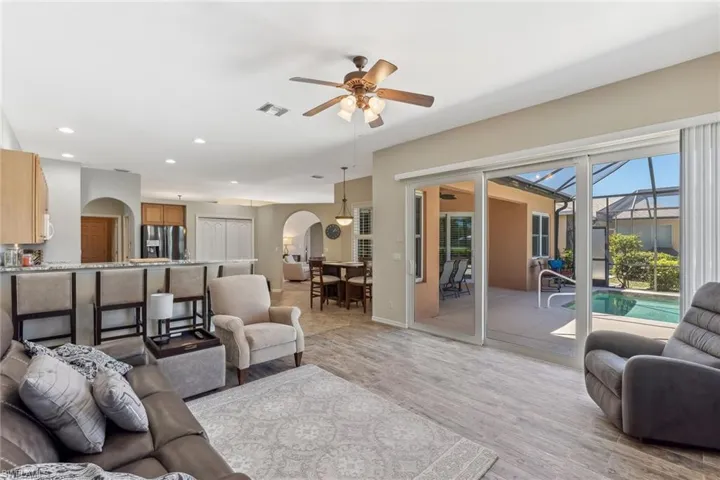 Living room featuring visible vents, light wood-style flooring, recessed lighting, arched walkways, and a ceiling fan
