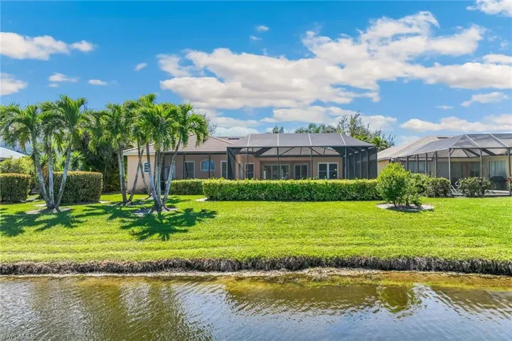 Rear view of property with a yard, a water view, a lanai, and stucco siding