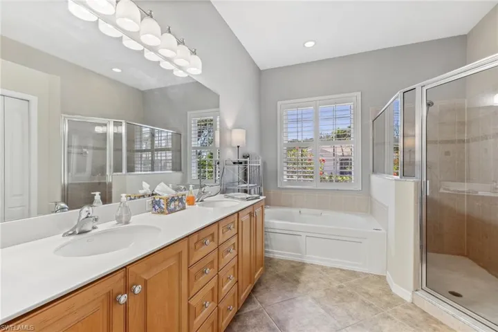 Full bath with tile patterned floors, double vanity, a stall shower, and a sink