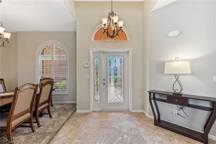 Foyer with baseboards, an inviting chandelier, and tile patterned flooring