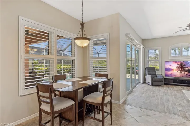 Dining space with light tile patterned floors, a ceiling fan, baseboards, and a wealth of natural light