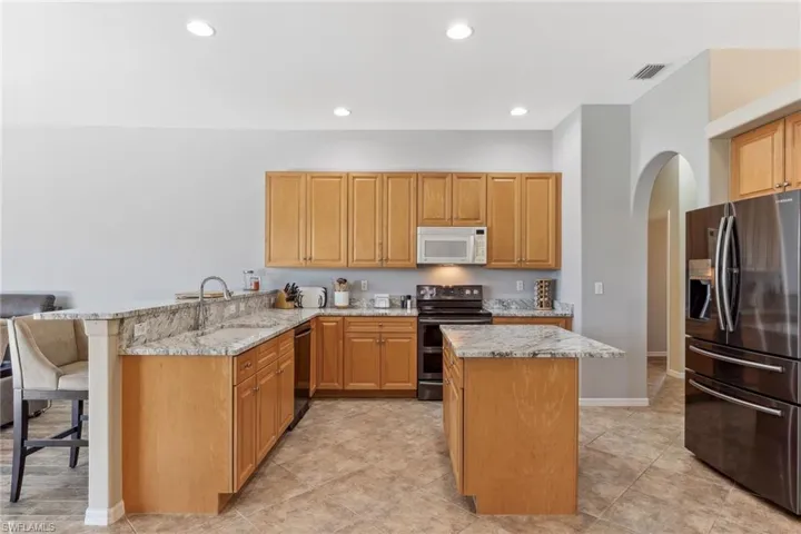 Kitchen with refrigerator with ice dispenser, double oven range, a peninsula, white microwave, and dishwasher