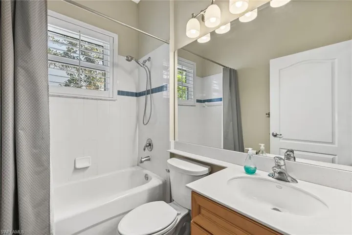 Bathroom with vanity, toilet, and shower / bathtub combination with curtain
