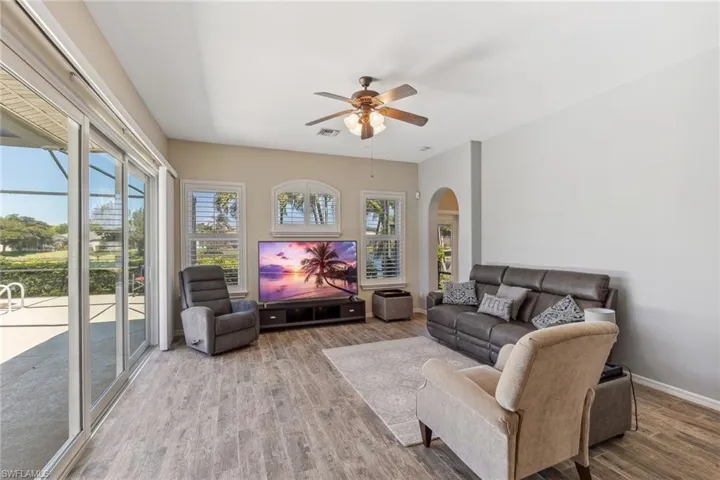 Living room with visible vents, baseboards, wood finished floors, arched walkways, and a ceiling fan