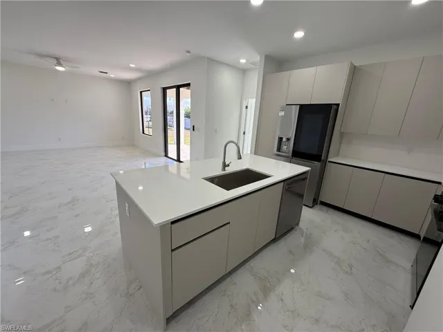 Kitchen with gray cabinetry, a kitchen island with sink, modern cabinets, open floor plan, and recessed lighting