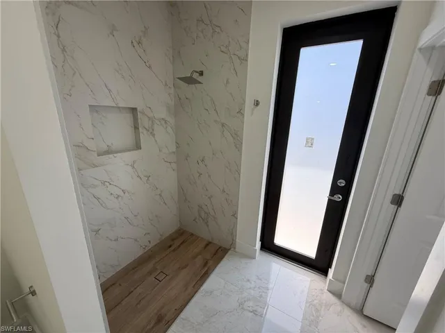Bathroom featuring light marble finish flooring and a marble finish shower