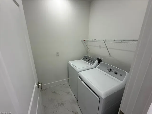 Laundry room with light marble finish flooring and washer and dryer