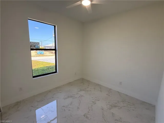 Spare room featuring a ceiling fan and light marble finish floors