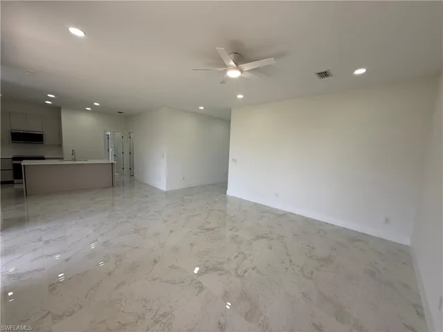 Unfurnished living room with light marble finish floors, a ceiling fan, and recessed lighting
