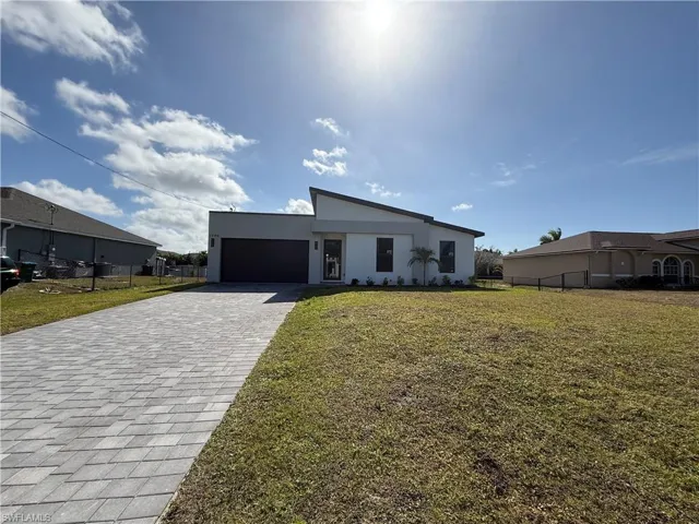 View of front of house featuring decorative driveway, an attached garage, and stucco siding