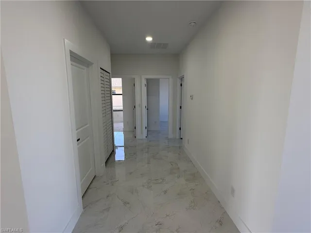 Corridor featuring light marble finish floors and recessed lighting