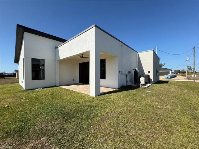 Rear view of property featuring a patio area, ceiling fan, a yard, and stucco siding