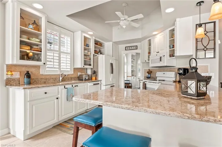 15437 Puffin Drive Bonita Springs FL 34135- open kitchen with glass front cabinets, Cambria countertops, tile backsplash, and cast iron sink.