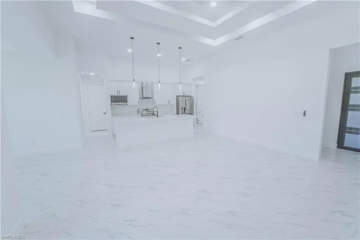Unfurnished living room featuring light tile patterned flooring, sink, and a raised ceiling