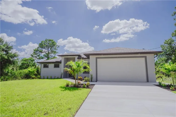 View of front facade featuring a garage and a front lawn